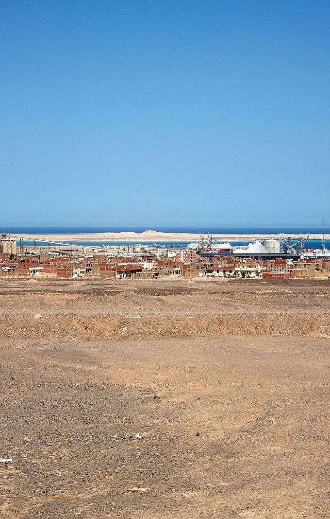 File photo of Safaga seen across open desert ground, with the port's cranes, silos and a moored vessel along the shoreline behind the town. Archive image, not the planned logistics centre.