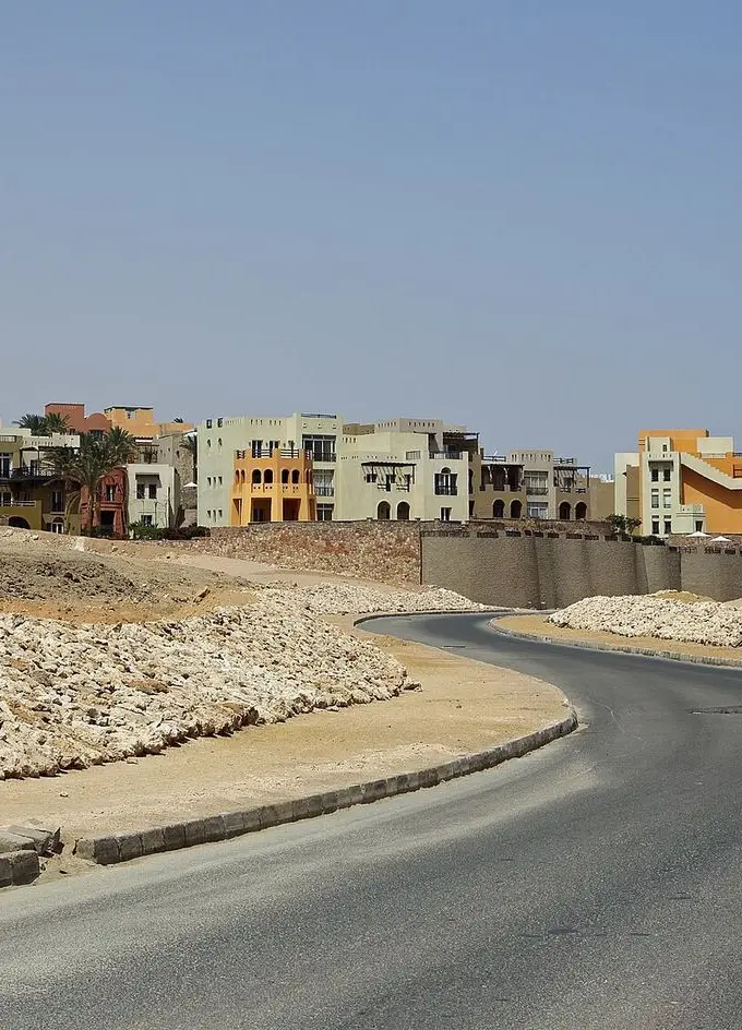 A road curving through Sahl Hasheesh, with completed resort buildings on one side and bare, undeveloped rocky ground on the other. File photograph of the area, not a picture of the 375-feddan plot named in the letter.